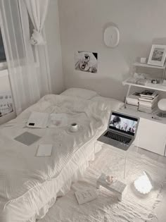 a laptop computer sitting on top of a bed next to a white dresser and window