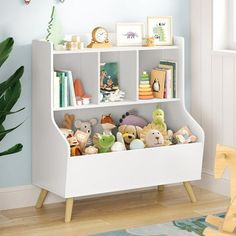 a white book shelf with stuffed animals on it in a child's room next to a potted plant