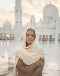 a woman standing in front of a large white building with arches and domes on it