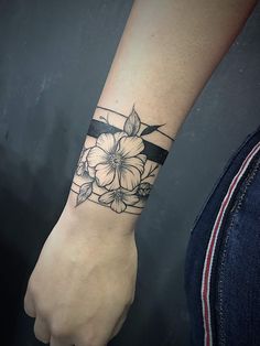 a woman's arm with a flower tattoo on her left wrist and a black ribbon around the wrist