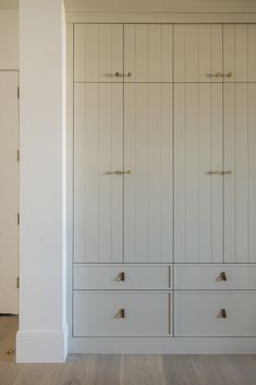 an empty room with white cabinets and wood floors