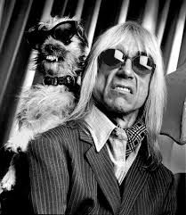 a man with long hair and sunglasses holding a dog