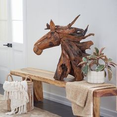 a wooden horse head sitting on top of a bench next to a potted plant