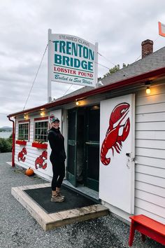 a person standing outside of a building with a lobster sign on it's side