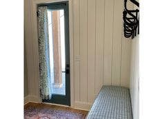 a room with a bench, rug and door