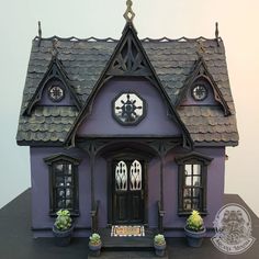 a purple doll house with black roof and windows