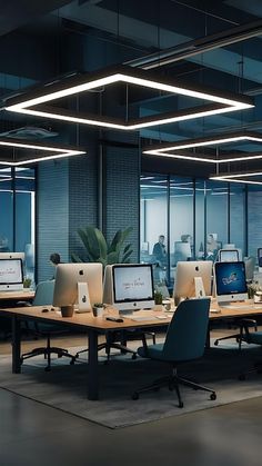 there are many computers on the desks in this large office space with glass walls and floor to ceiling windows