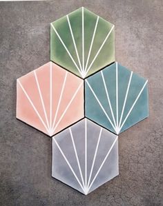 three hexagonal tiles with lines painted on them in different colors and shapes, one is green, the other is pink