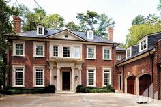 a large brick house with two garages on each side and three windows in the middle