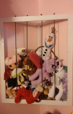 a bunch of stuffed animals are in a caged area on the wall next to a teddy bear