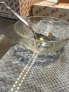 a glass bowl with a spoon in it sitting on a table next to some boxes