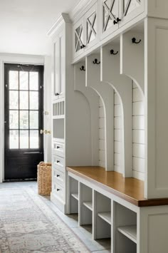 a white entryway with built in benches and storage units on either side of the door