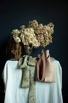 three vases with flowers in them sitting on a white table cloth next to each other