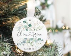 a personalized ornament hanging from a christmas tree with greenery on it