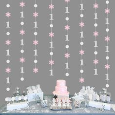 a table topped with a pink cake next to a wall covered in snowflakes