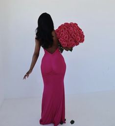 a woman in a long pink dress holding a large bouquet of roses on her shoulder