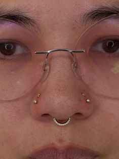 a close up of a person wearing glasses with nose piercings on his nose and nose ring