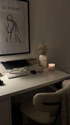 a white desk topped with a laptop computer next to a vase filled with flowers and candles