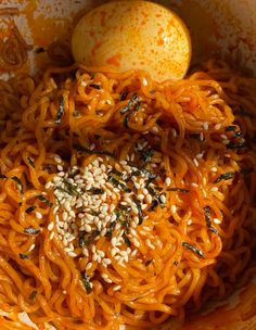 an egg is sitting on top of noodles in a bowl with sesame seeds and seaweed