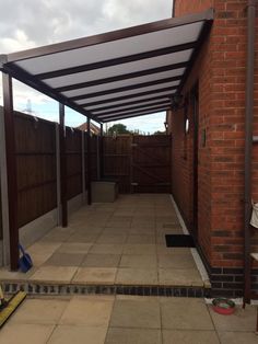 an outdoor patio area with brick walls and tiled flooring, covered by a metal awning