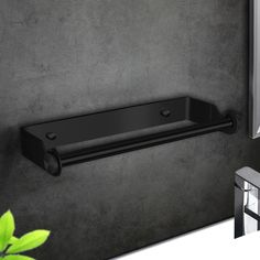 a black towel rack on the wall next to a window with green plants in it