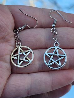 Silver pentacle earrings, pentagram earrings, witchy statement jewelry, alternative fashion accessory, gothic gift ideas for her These pentacle earrings are the perfect gift for anyone in your local coven. Charms are nickel free while the fishhooks are made from sterling silver so they are safer for more sensitive ears. If you would rather have clipons or leverbacks please leave it as a note to seller! Both earrings and my workspace are properly sanitized to ensure your safety during these unpre Gothic Star-shaped Pierced Earrings, Gothic Silver Star Earrings, Silver Star Gothic Earrings, Gothic Star-shaped Metal Earrings, Gothic Star Shaped Metal Earrings, Pentacle Earrings, Pentagram Earrings, Jewelry Alternative, Gothic Gifts