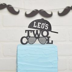 a blue cake with a mustache and sunglasses on top that says leo's two cool