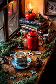 a cup of coffee sitting on top of a wooden table next to books and christmas decorations