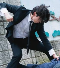 a man in a suit and tie is being pushed by another man on the ground