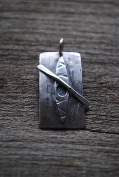 a small square pendant with a pair of scissors on it