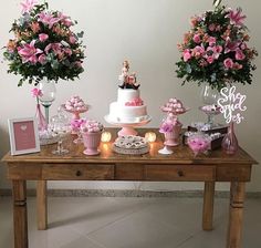 the table is covered with pink flowers and cupcakes