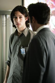 a young man standing next to another person in a room