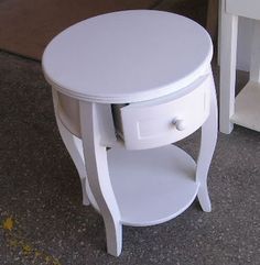 a small white table with one drawer on the side and another in the back ground