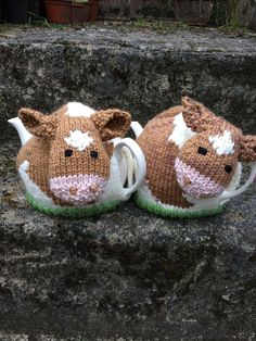 two brown and white knitted cow slippers sitting on top of a stone wall