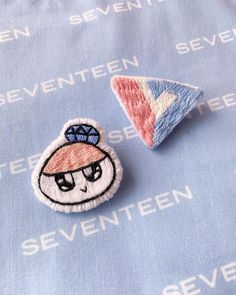 two embroidered badges sitting on top of a blue cloth