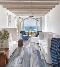 a living room filled with furniture and a large window overlooking the ocean on top of a wooden floor