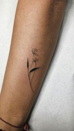 a woman's arm with a small flower tattoo on the left side of her leg