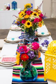 a table set with colorful flowers and place settings