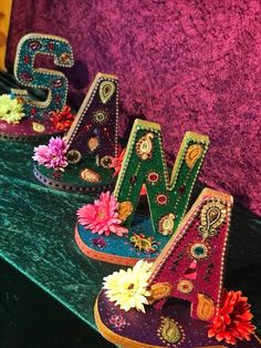 the letters are decorated with flowers and beads on top of a green table next to a purple wall