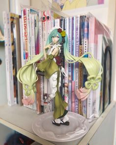 an anime figurine sitting on top of a book shelf next to a bunch of books