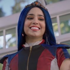 a close up of a person with blue hair wearing a costume and smiling at the camera