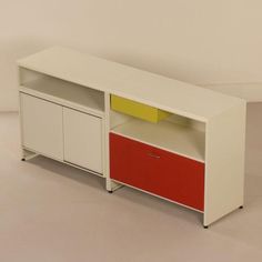 a white and red cabinet sitting on top of a floor next to a yellow shelf