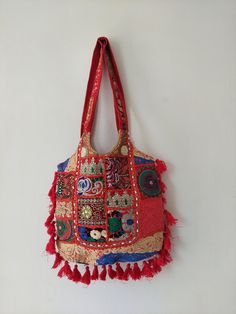 This beautiful Bohemian design shoulder bag is part of our ethically sourced fairtrade bag collection. Pair it with ethnic and western outfits. It is very easy to carry with ample of space and will definitely boost your look and personality with the great artwork. Crafted with a mixture of antique and recycled fabrics our magical beaded shoulder bags are something a bit special. Crafted from hand selected fabrics , twinned with complementing shades and textile features, beads, sequins, gemstones Red Bohemian Shoulder Bag With Tassels, Traditional Festive Bags With Tassels, Vintage Embroidered Bags For Festivals, Rectangular Bags With Multicolor Embroidery And Tassels, Red Bohemian Shoulder Bag, Bohemian Festival Shoulder Bag, Everyday Festival Bags With Tassels, Bohemian Multicolor Embroidered Hobo Shoulder Bag, Red Rectangular Bags With Motifs