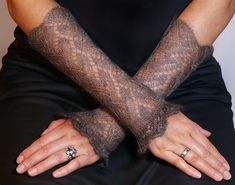 a woman's hands are covered with black lace gloves and ring fingerless gloves