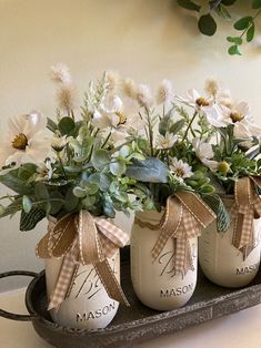 three mason jars with flowers in them on a tray