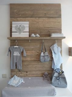 a baby's room is decorated with wooden pallets and hanging clothes on the wall