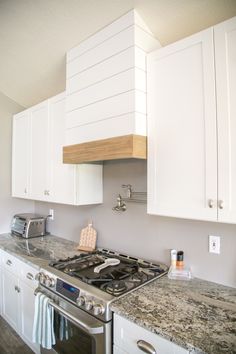 a stove top oven sitting inside of a kitchen next to white cabinets and counter tops