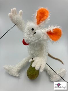 a white stuffed animal with an orange nose and tail, holding a green object in its paws