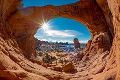 the sun is shining through an arch in the desert