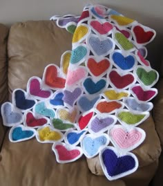 a pile of heart shaped pillows sitting on top of a brown pillow covered in multicolored hearts